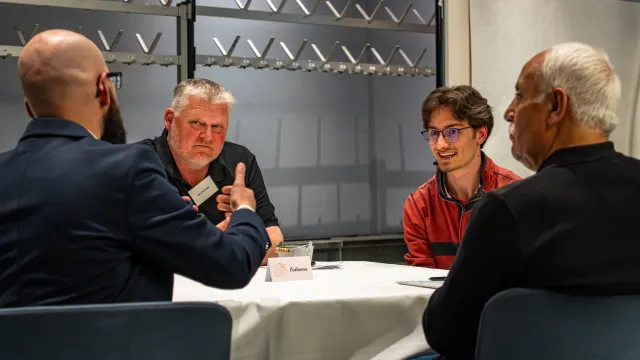 Vier Männer sitzen um einen Tisch und diskutieren
