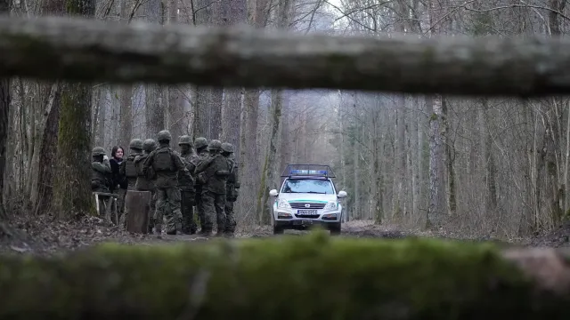 Polizeiauto und eine Gruppe von Grenzbeamten im Wald zwischen Belarus und Polen