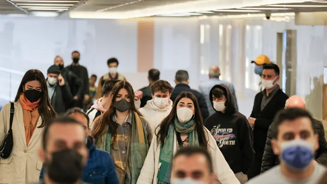 Mehrere Personen tragen eine Maske und laufen in eine Richtung.