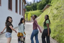 Das Bild zeigt Nacha, Garima, Diariou und Kiara, vier Schüler:innen des UWC Robert Bosch College in Freiburg, auf dem Schulhof. Sie lachen in die Kamera. 
