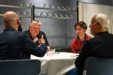Vier Männer sitzen um einen Tisch und diskutieren