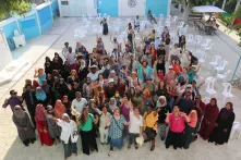Eine große Gruppe von Frauen steht in einem Hof uns winkt in die Kamera. Das Bild zeigt Friedensstifterinnen auf einer Versammlung auf den Malediven 2025