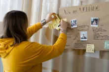Eine Teilnehmerin des Vidnova Fellowship Programms heftet Zettel an ein Plakat mit der Aufschrift "We are Ukraine"