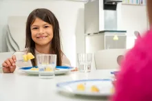 Schülerin am Tisch in der Schulkantine mit Kartoffeln auf dem Teller
