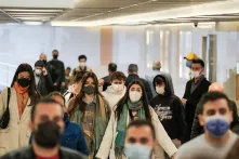 Mehrere Personen tragen eine Maske und laufen in eine Richtung.