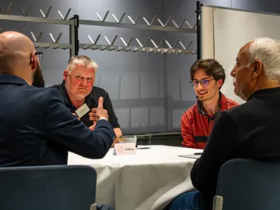 Vier Männer sitzen um einen Tisch und diskutieren