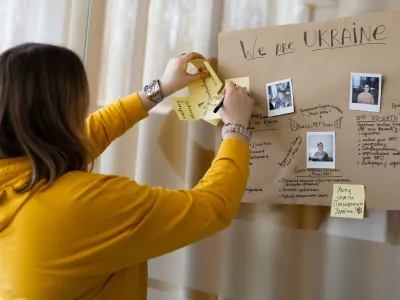 Eine Teilnehmerin des Vidnova Fellowship Programms heftet Zettel an ein Plakat mit der Aufschrift "We are Ukraine"