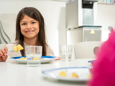 Schülerin am Tisch in der Schulkantine mit Kartoffeln auf dem Teller