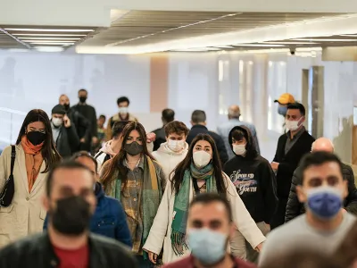 Mehrere Personen tragen eine Maske und laufen in eine Richtung.