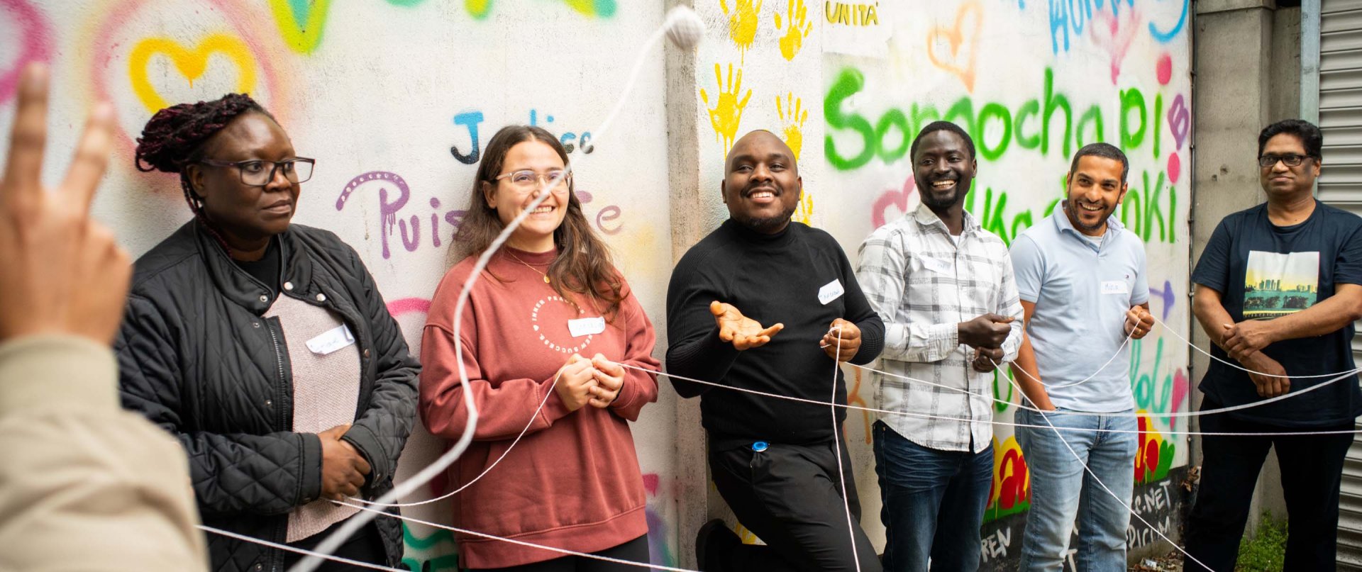 Menschen stehen im Halbkreis und werfen sich ein Wollknäuel zu