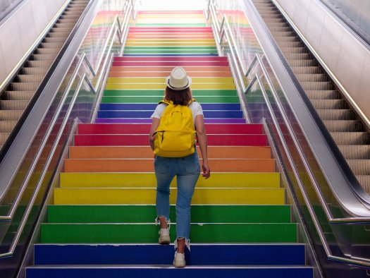 Mensch geht Treppe mit bunt gefärbten Stufen hoch